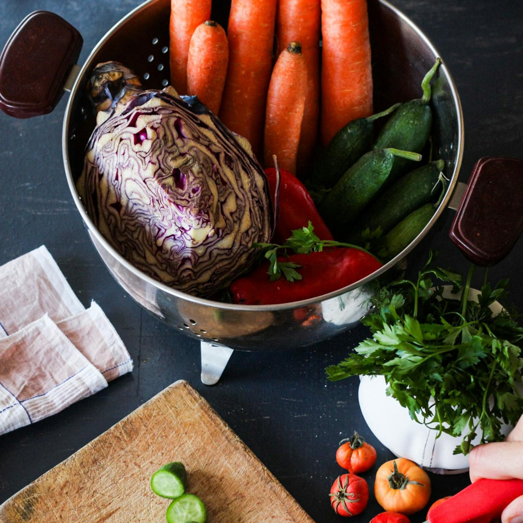 Sliced cucumbers and fresh veggies on a cutting board for healthy meal prep.